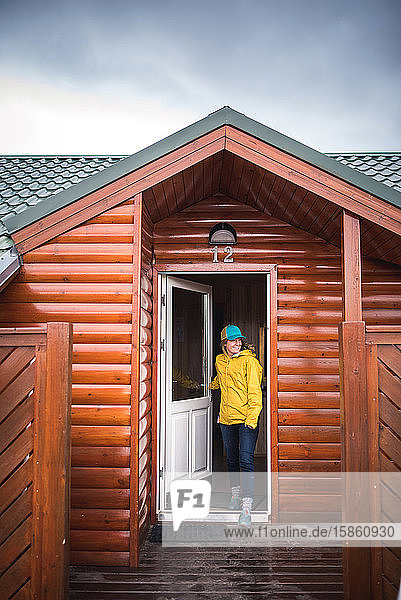Frau in Gelb geht durch die Haustür eines Hauses in Island