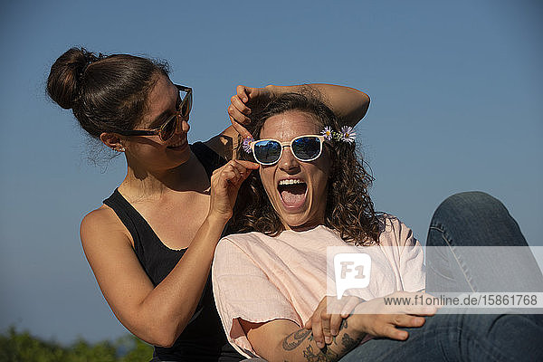 Zwei lachende Frauen an einem sonnigen Tag im Freien.
