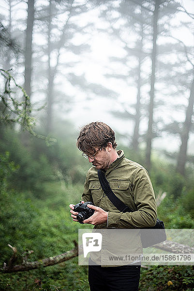 Photographer looking at camera outdoors in forest setting