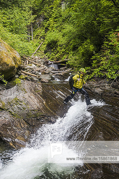 Hiker steps over small waterfall in the lower section of Frost Creek.