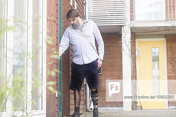 älterer Mann mit Beinprothese kommt nach Hause