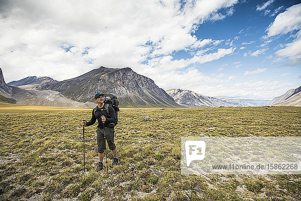 Backpacker hiking through open valley in the arctic.