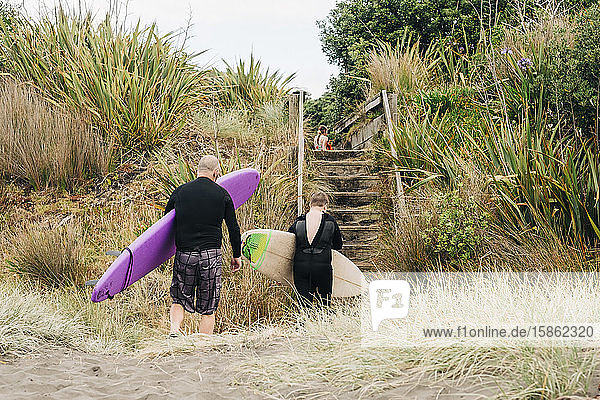 Familie mit Surf- und Boogie-Boards verlässt den Strand