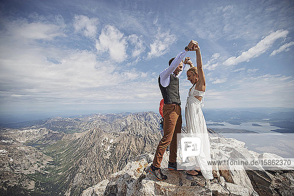 Braut und Bräutigam feiern nach der Heirat auf dem Gipfel des Berges