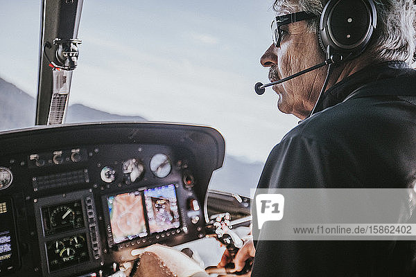 Baby boomer aged man enjoys flying helicopter in the mountains.