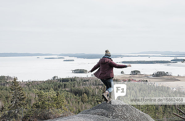 Frau springt auf Felsen  während sie in Schweden auf einen Berg wandert