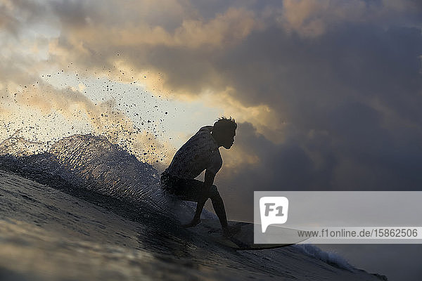 Surfer on a wave at sunset time