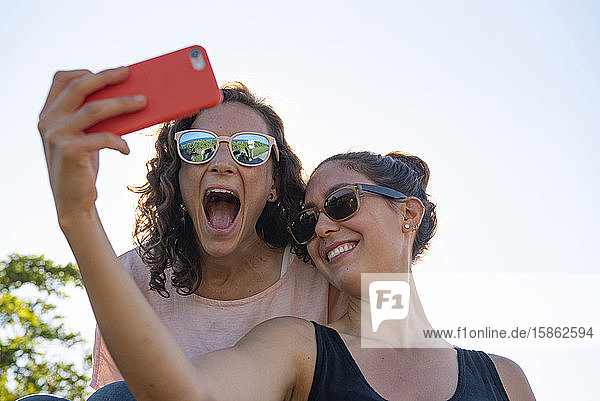 Zwei Freundinnen  die für einen Selfie lächeln