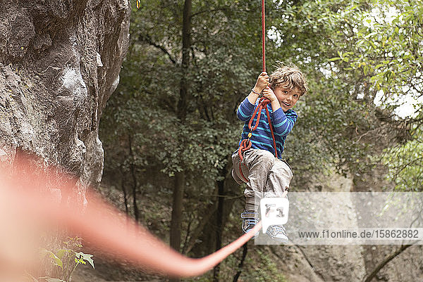Vierjähriges Kleinkind schwingt an einem Kletterseil hängend