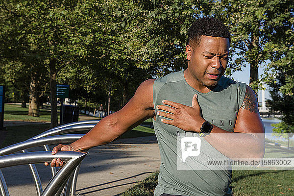 athletic man in running gear stretches in a city park