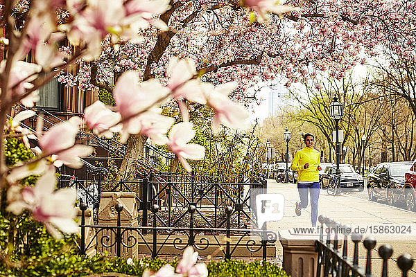 A woman running down a city street in Boston at springtime.