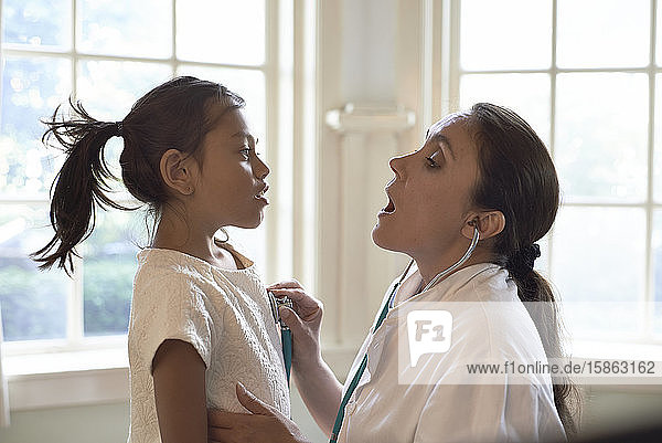 General Practitioner using a stethoscope during check-up a young girl