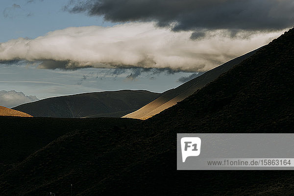 dramatisches Sonnenlicht trifft auf einen fernen Berghang in der Nähe des Lindis-Passes  Neuseeland
