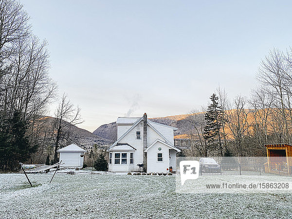 Blick in den Hinterhof auf den gefrosteten Rasen und das Haus mit Bergblick im Winter