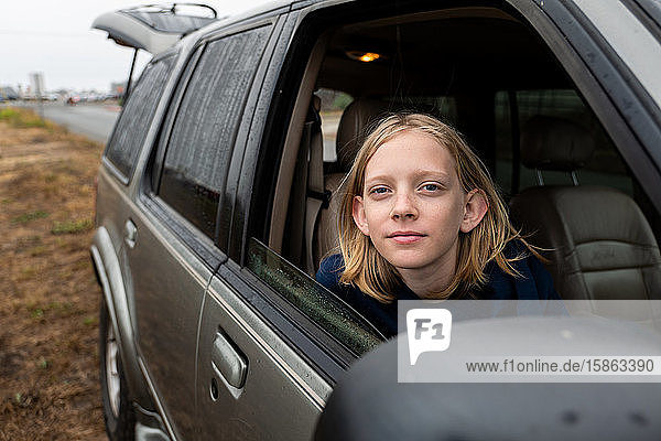 Tween looking at camera from passenger seat of SUV