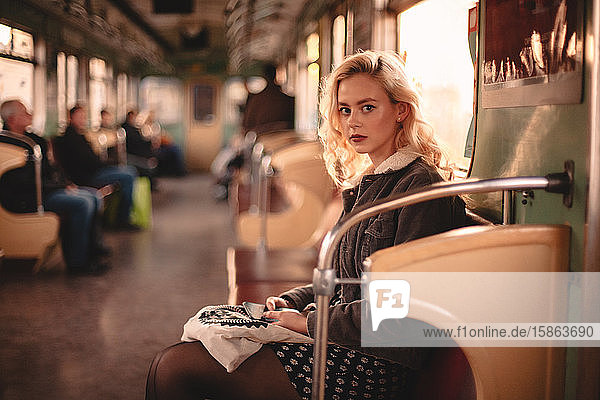Young woman looking at camera while traveling in subway train