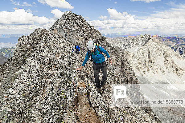 Women climb narrow ridge on Capitol Peak  Elk Mountains  Colorado