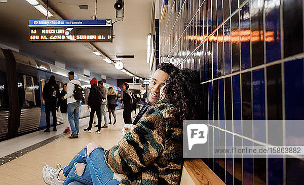 Paar  das in der U-Bahn-Station sitzt und gemeinsam auf einen Zug wartet