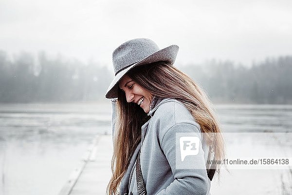 Profil einer Frau mit langen braunen Haaren und einem Hut auf lächelndem Lächeln