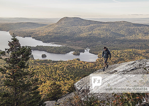 male hiker walks along cliff with view on Appalachian Trail  Maine