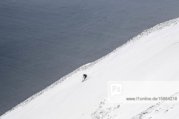 Eine Frau  die in Island auf Skiern zum Ozean fährt.