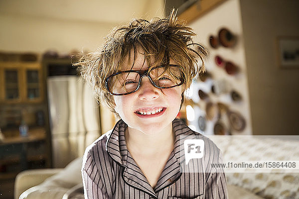 Porträt eines sechsjährigen Jungen mit zerzaustem Haar und übergroßer Brille beim Aufwachen. Betthaar.