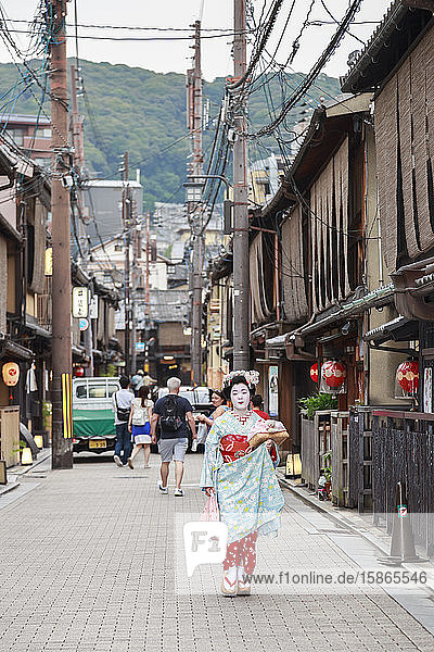 Maiko  Geisha-Lehrling  geht zur Abendverabredung an traditionellen Holzgebäuden vorbei  Gion  Kyoto  Japan  Asien