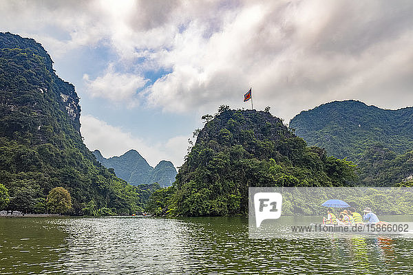 Boat tours in the Red River along the shoreline with limestone rock formations; Ninh Binh  Ninh Binh  Vietnam