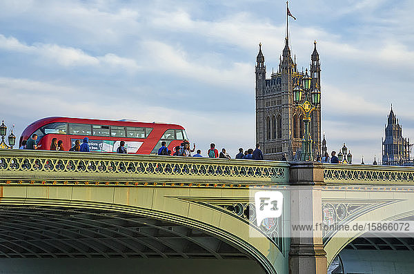 London Bridge with pedestrians and a bus and Victoria Tower at the Palace of Westminster in the background; London England