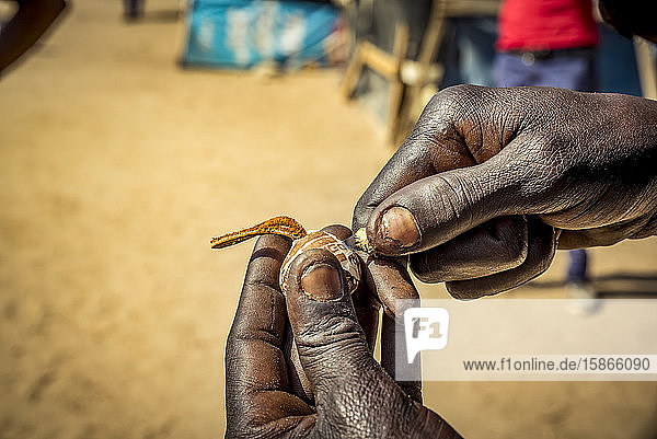 Man's hands intricately making an item to sell at the Okahandja Mbangura Woodcarvers Craft Market; Okahandja Otjozondjupa Region Namibia