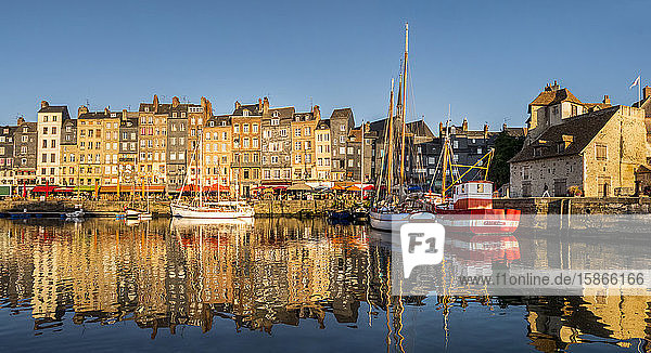 Boats and buildings reflected in the tranquil water of the harbour; Honfleur Normandy France