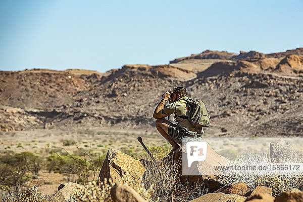 Tourist with binoculars at Twyfelfontein an ancient rock engravings site in Damaraland; Kunene Region Namibia