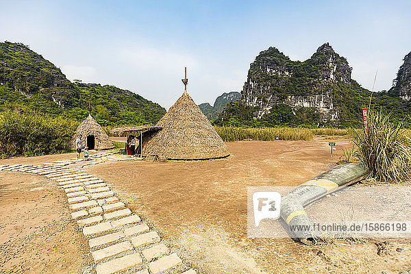 Tourists at thatch structures and limestone karsts Ninh Binh landscape; Ninh Binh Province Vietnam