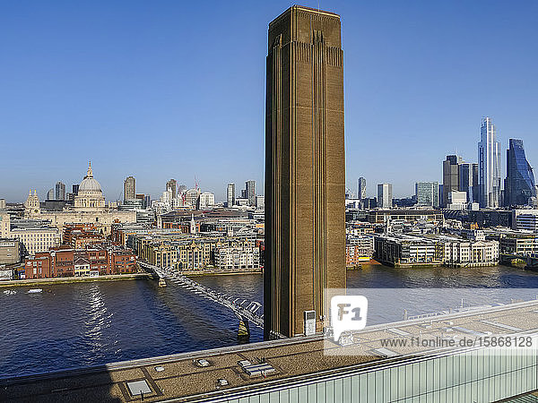 Schornstein des Kunstmuseums Tate Modern und die Millennium-Brücke über die Themse mit einer Stadtansicht von London; London  England