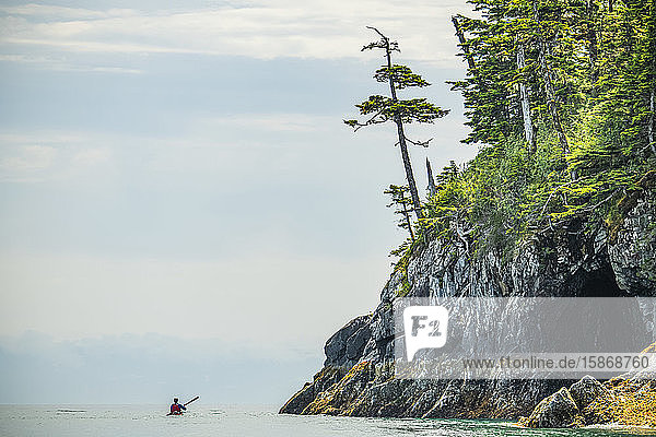 Kayaker paddling through the calm waters in the beautiful scenery of Prince William Sound; Alaska United States of America