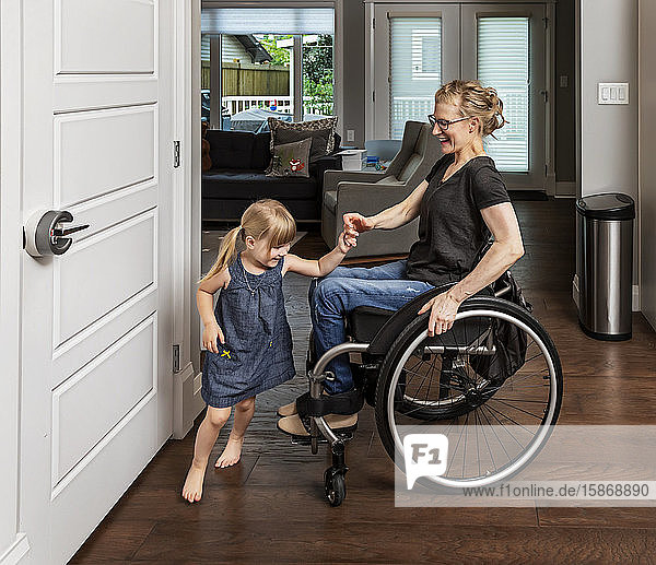 Eine querschnittsgelähmte Mutter tanzt mit ihrer Tochter in der Küche und benutzt dabei ihren Rollstuhl: Edmonton  Alberta  Kanada