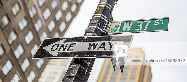 Straßenschilder an einem Pfosten  eine Einbahnstraße und West 37th Street  Manhattan; New York City  New York  Vereinigte Staaten von Amerika