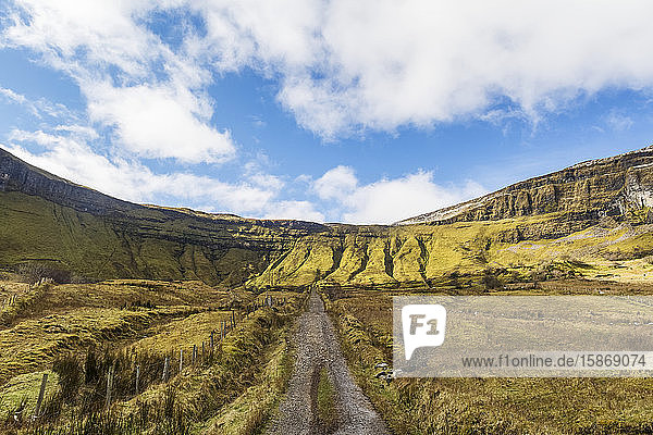 Alte irische Schotterstraße  die zu steilen Klippen und Bergen führt  im Sonnenlicht an einem sonnigen Tag mit Wolken am Himmel; Eagles Rock  County Leitrim  Irland