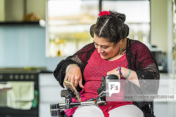 Maori-Frau mit zerebraler Lähmung im Rollstuhl  die ein Smartphone benutzt; Wellington  Neuseeland