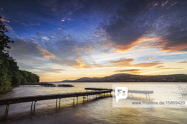 Dock am Ufer eines Sees mit Bergen im Hintergrund bei Sonnenaufgang; Two Mile Gate  Grafschaft Clare  Irland