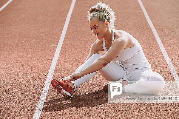 Frau bindet ihre Schnürsenkel  um sich auf das Laufen auf einer Bahn vorzubereiten; Wellington  Neuseeland