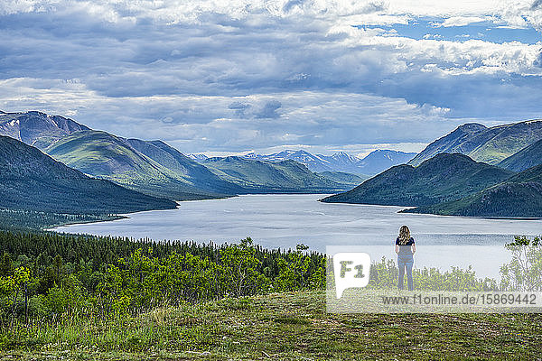 Frau steht und schaut auf einen See und die weiten Yukon Ranges; Whitehorse  Yukon  Kanada