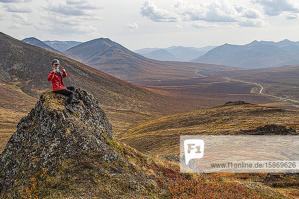 Frau bei der Erkundung der Berge entlang des Dempster Highway im Herbst; Yukon  Kanada