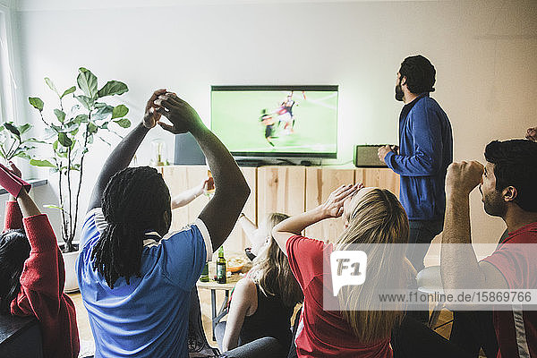 Fans jubeln  während sie zu Hause ein Fußballspiel im Fernsehen verfolgen