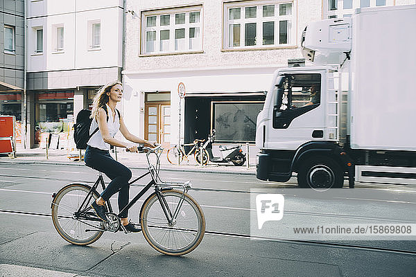 Jungunternehmer in voller Länge mit dem Fahrrad auf der Straße in der Stadt