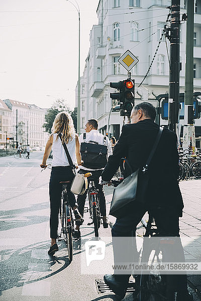 Geschäftskollegen in voller Länge mit dem Fahrrad auf der Straße in der Stadt