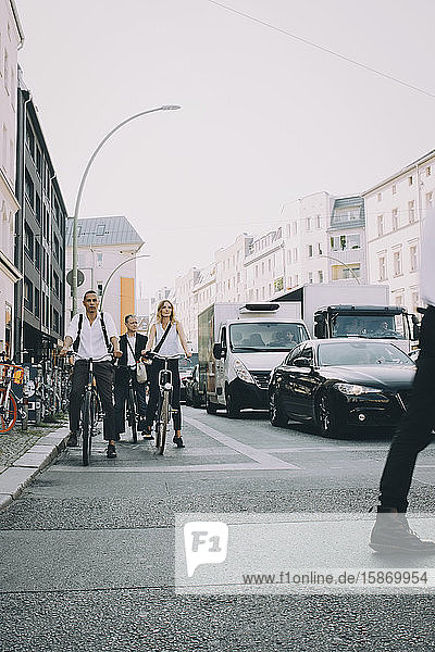 Vollständige Länge der männlichen und weiblichen Mitarbeiter  die in der Stadt auf der Straße Fahrrad fahren
