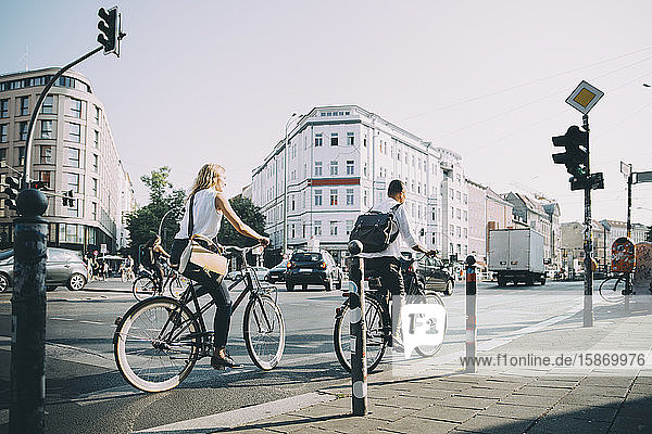 Unternehmer und Unternehmerinnen in voller Länge mit dem Fahrrad auf der Straße in der Stadt