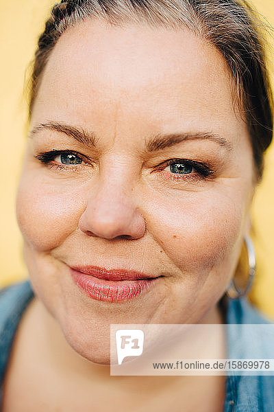 Nahaufnahme-Porträt einer lächelnden Frau vor gelbem Hintergrund