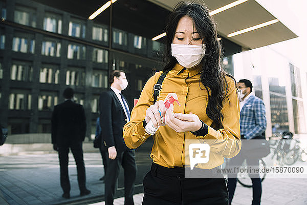 Woman with face mask using hand sanitizer